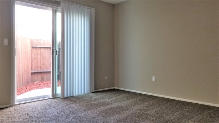 Bedroom with plush carpeting and patio access via sliding glass door, alternate view